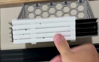 3D printed honeycomb build plate holder mounted under a shelf, loaded with Bambu Lab A1 mini build plates